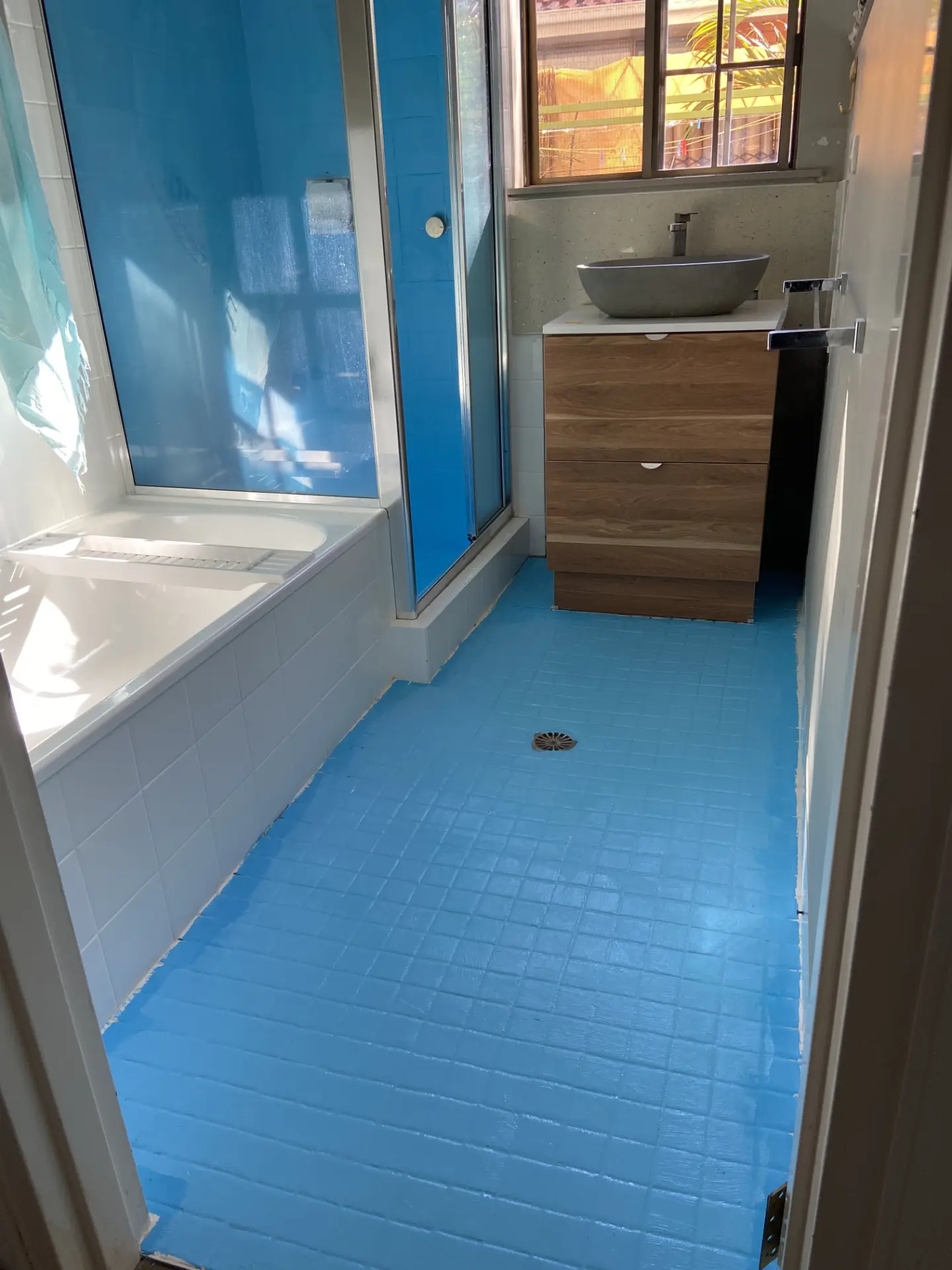 Bathroom floor with blue waterproofing membrane applied over the existing tiles before tile over tile installation