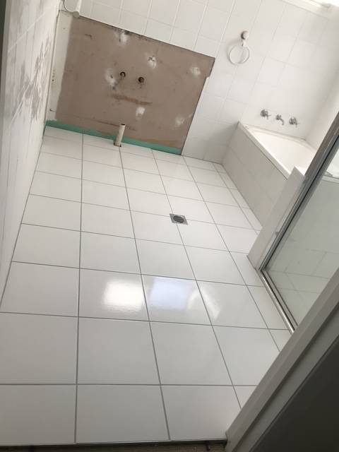 Finished white bathroom floor tiles laid over the existing tiles after a tile over tile installation