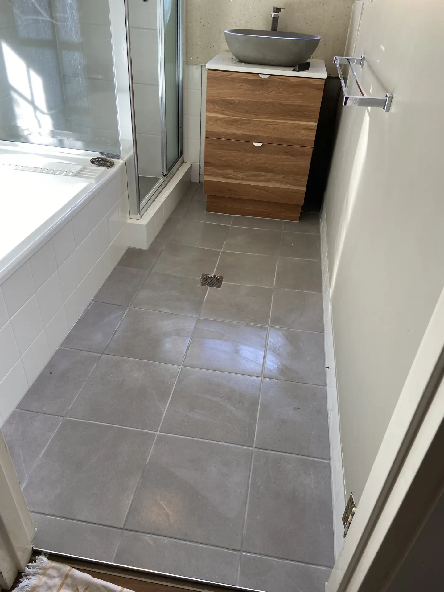 Finished grey floor tiles laid directly over the existing tiles after a tile over tile installation